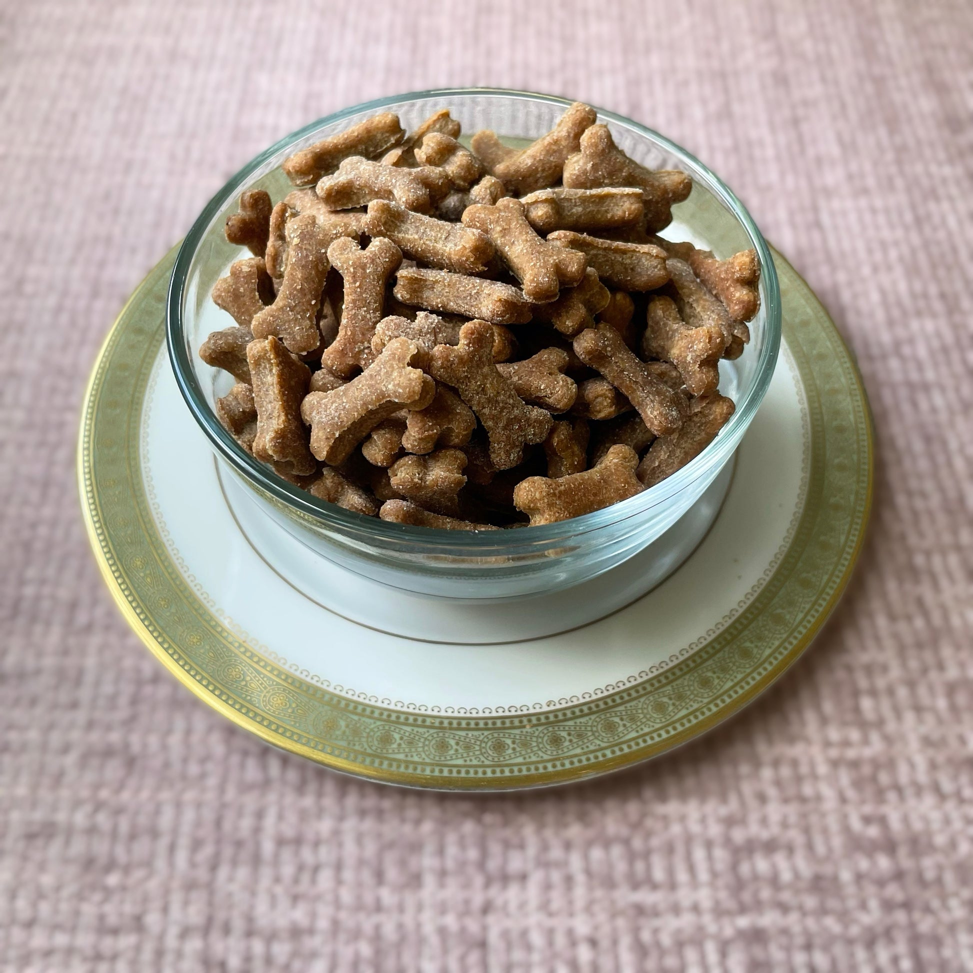 A glass bowl containing tiny peanut butter dog cookies in the shape of dog bones.