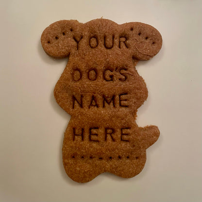 A dog cookie in the shape of a dog with "Your Dog's Name Here" personalized on it.